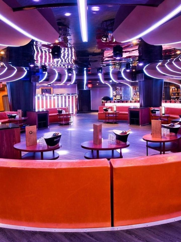 Strand's main floor with curved orange banquettes, round tables and light strips in the ceiling